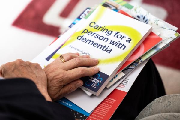A close up of a pile of Alzheimer's Society information booklets on a person's lap