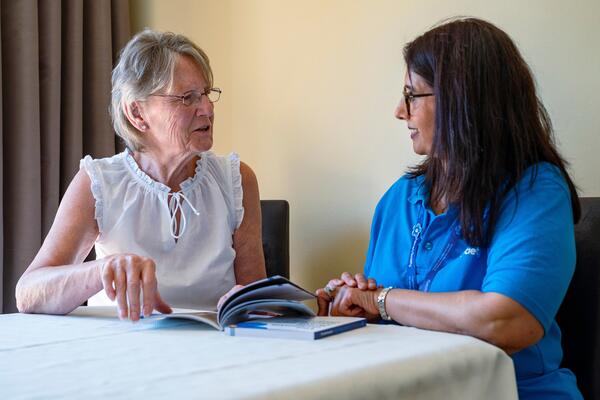 Two women read an Alzheimer's Society booklet at a table