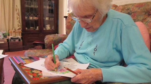 A woman with dementia sitting down and drawing