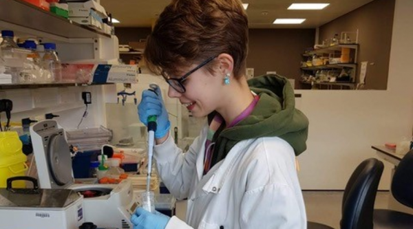 Joanne Sharpe, a researcher wearing a white lab coat, working in the lab