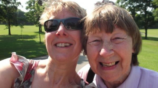 Sue smiling next to her mum on a sunny day