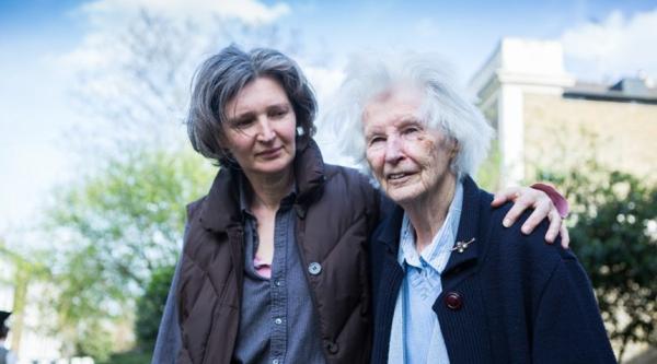 Carer walks with arm around person with dementia