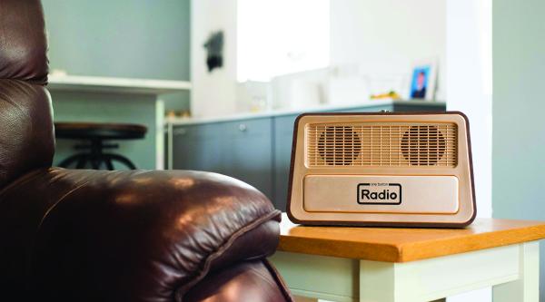 A close up of a dementia friendly radio on a side table next to an arm chair