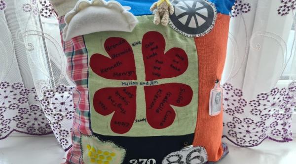 The front of Ting Ting's fidget cushion inspired by her granny, featuring four red hearts in a circle, a stitched Cornish pasty, and various other colourful objects