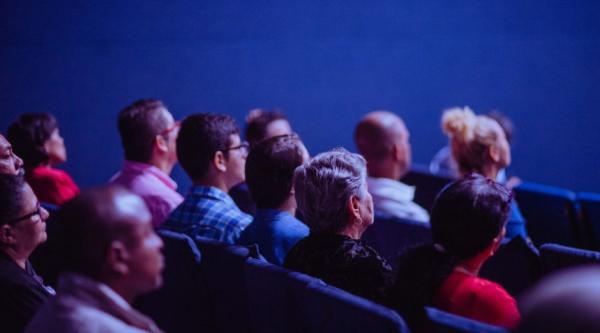A sideview of an audience in a cinema screening