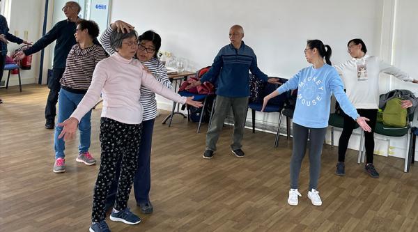 A group of people with dementia and carers take part in Qigong
