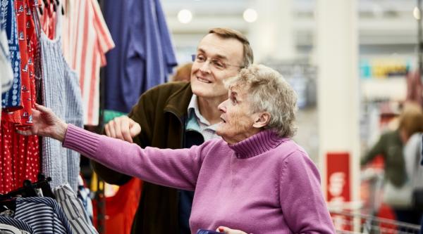 A person with dementia looking at clothes in a shop with a family member