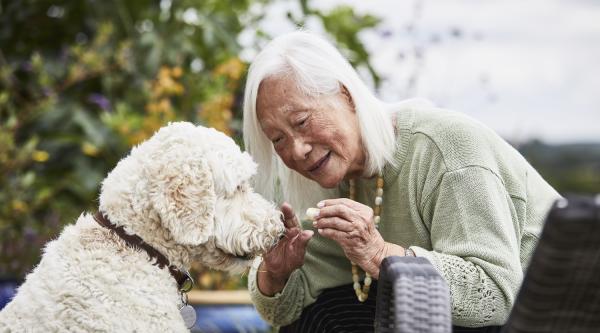 A lady with dementia gives her dog a treat