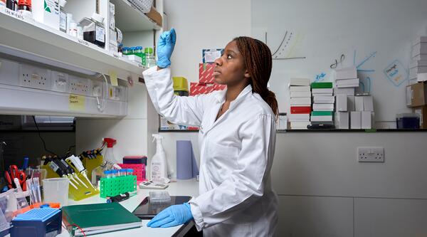 Researcher working in a lab, looking at a microscopic slide