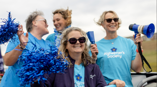 Three women with pom poms and megaphones cheer on AS runners