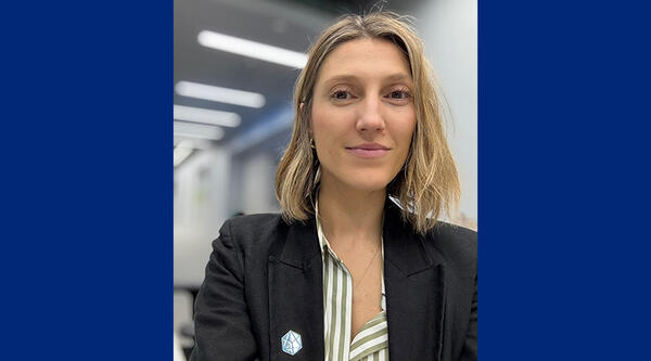 Magdalena has shoulder length blonde hair, she is wearing a black jacket and stripy shirt