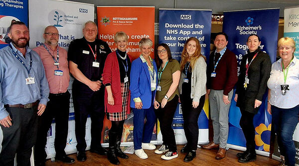 Professionals from Bassetlaw dementia peer support hub standing in front of advertising banners.
