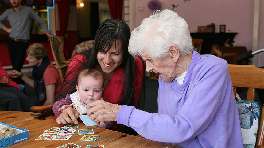 A resident interacts with a young child at a care home.