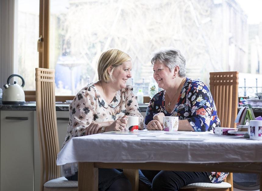 Two women sitting at a table laughing