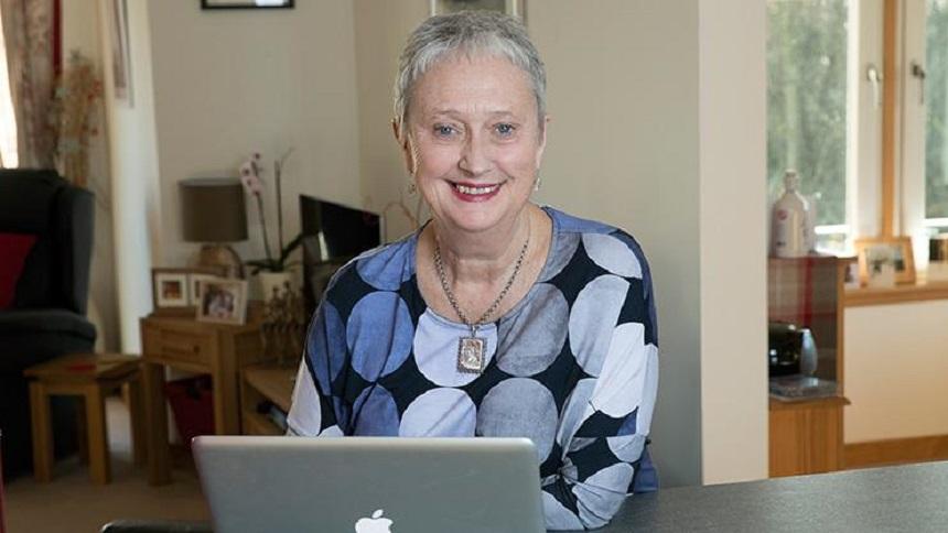 Woman sitting at a table, using a laptop