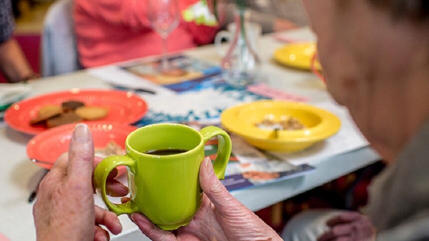A woman holding a green mug with two handles