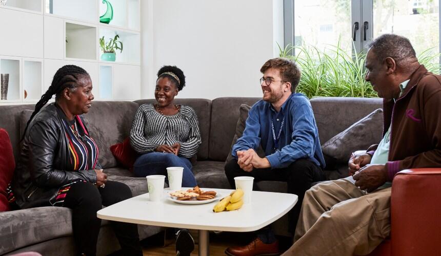 Four people relaxed in conversation on a sofa sitting around a table
