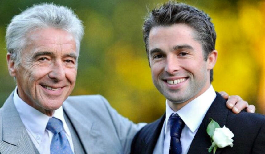 Charlie and his dad Nigel at a wedding, both wearing suits and smiling. Nigel's arm is around Charlie's shoulder.
