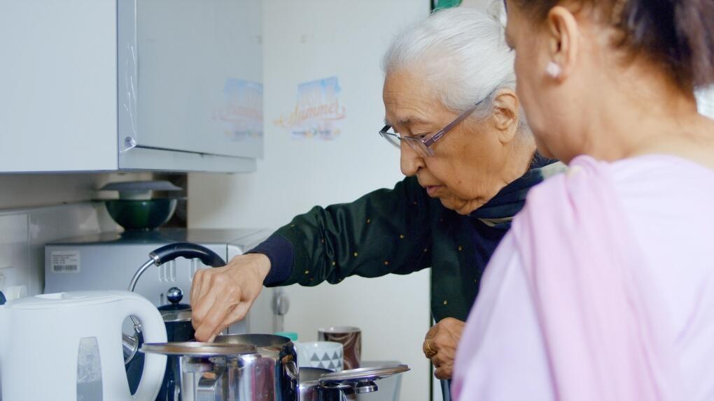 Two women making cups of tea in the kitchen