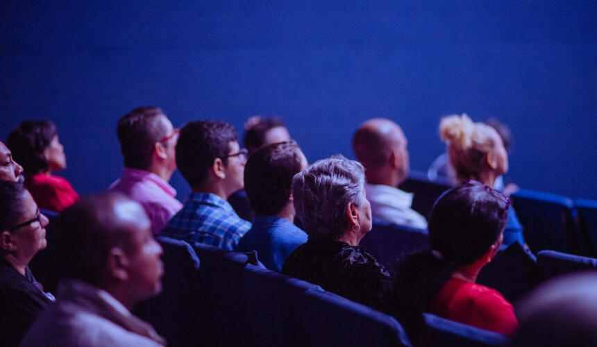 A sideview of an audience in a cinema screening