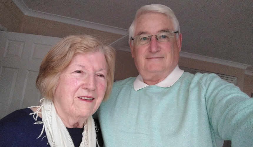 John and his partner smiling together indoors