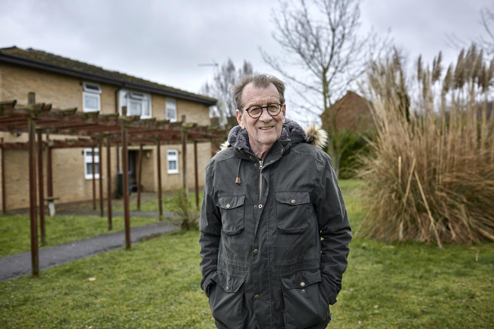 A man dressed in a coat on a cloudy autumnal day