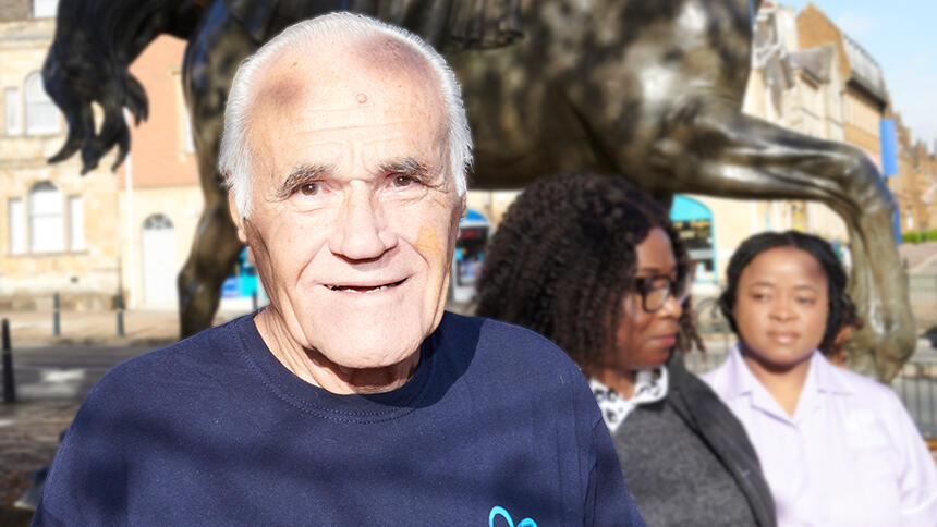 Bryan Talbot in a navy blue Alzheimer's Society t-shirt in front of a statue of a horse