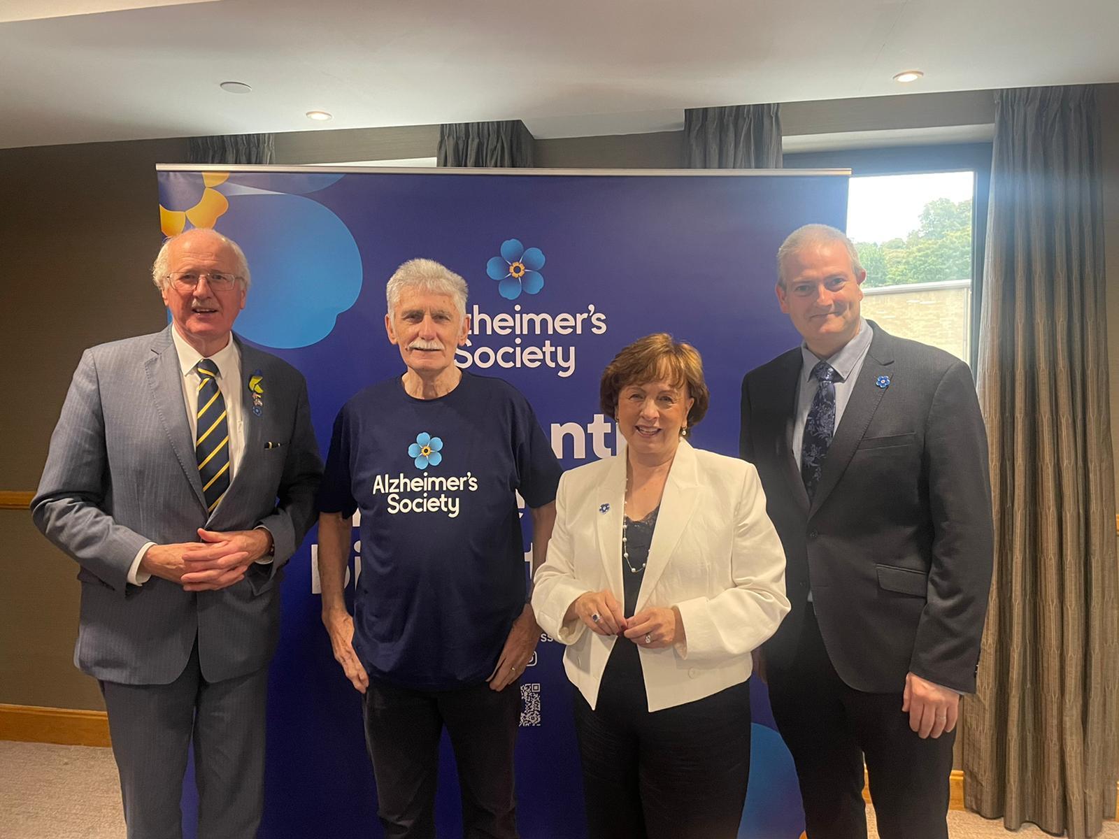 Jim Shannon MP, Alzheimer's Society Camapigner Jim, Diane Dodds MLA, National Influencing Officer Martin Reilly stood in front of Alzheimer's Society branding.