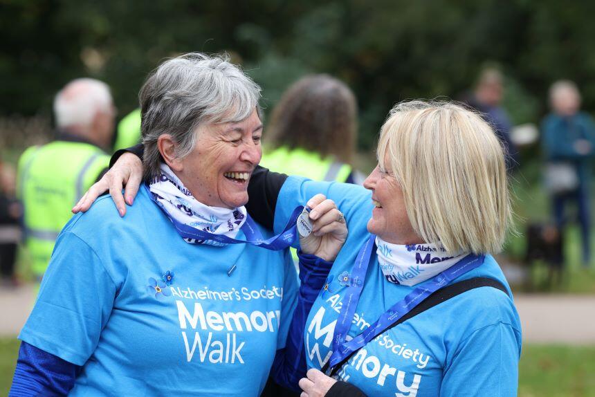 Two ladies in blue t-shirts smiling at each other