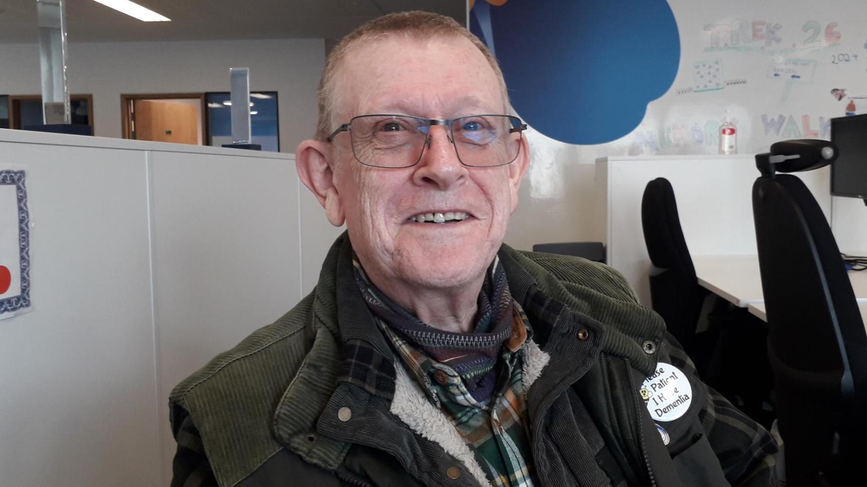 An almost bald man with glasses smiling