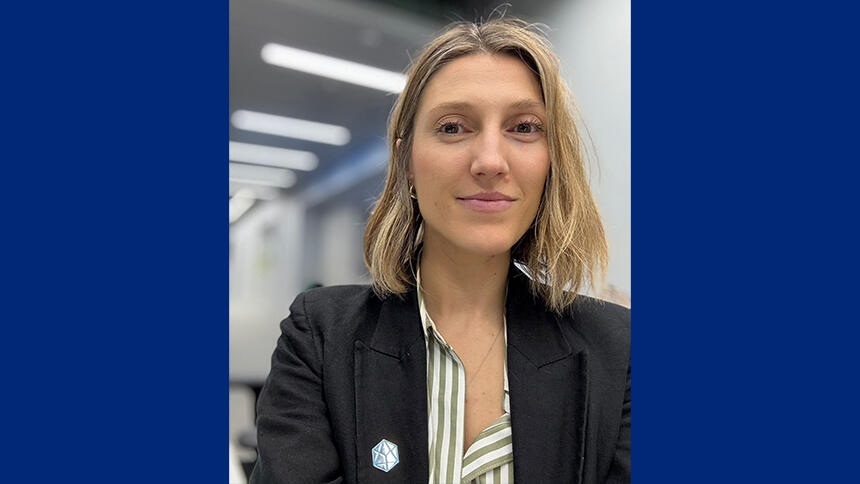 Magdalena has shoulder length blonde hair, she is wearing a black jacket and stripy shirt