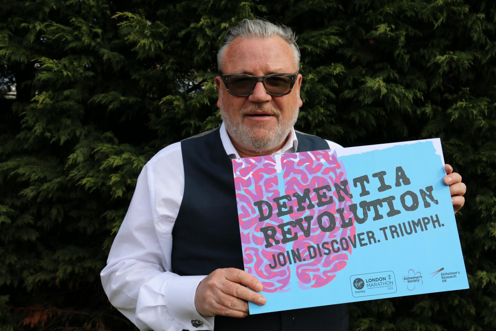 Ray Winstone holding a dementia revolution sign