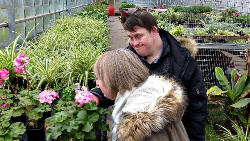 Couple with Down's syndrome smelling flowers