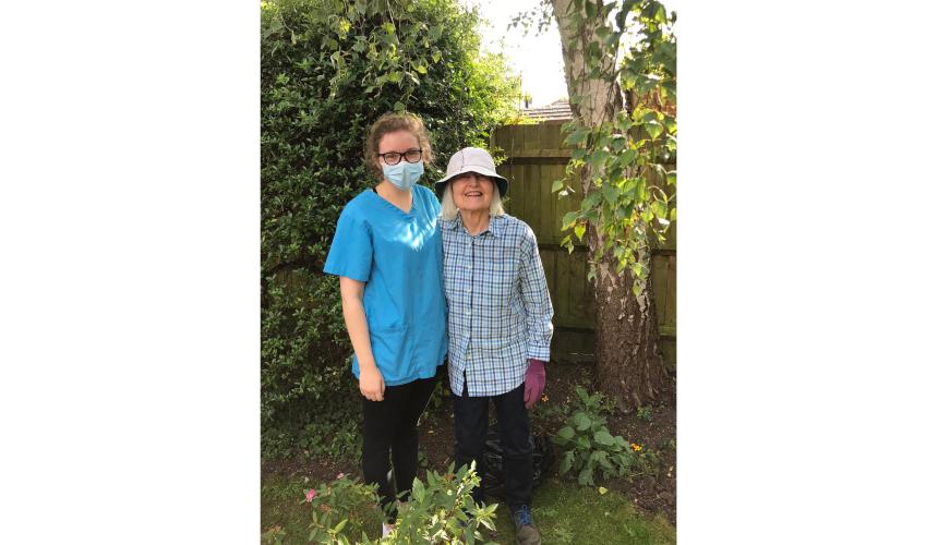 Ellie, a care home worker, wearing a mask and standing beside a resident