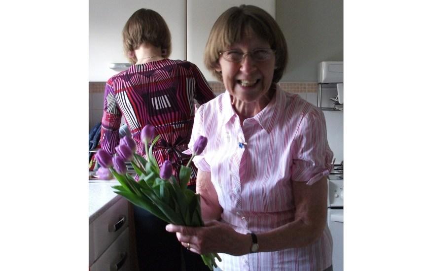 Sue's mum smiling holding flowers