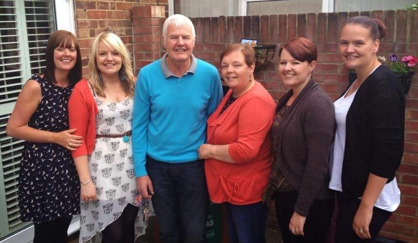 Jen with her parents and three sisters, standing together in the garden, smiling