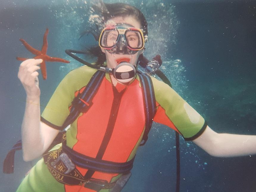 Ann holding a starfish while diving underwater