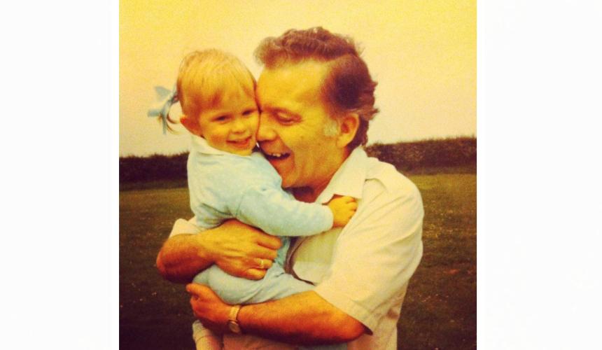 An old photo of Natasha as a child being cuddled by her granddad