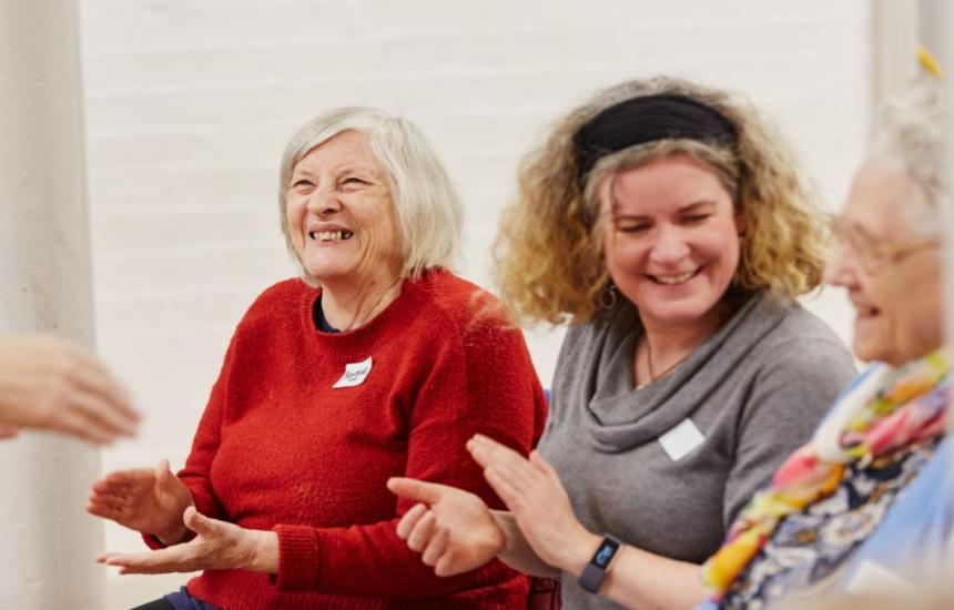 Three women in a dementia friendly group, laughing and clapping