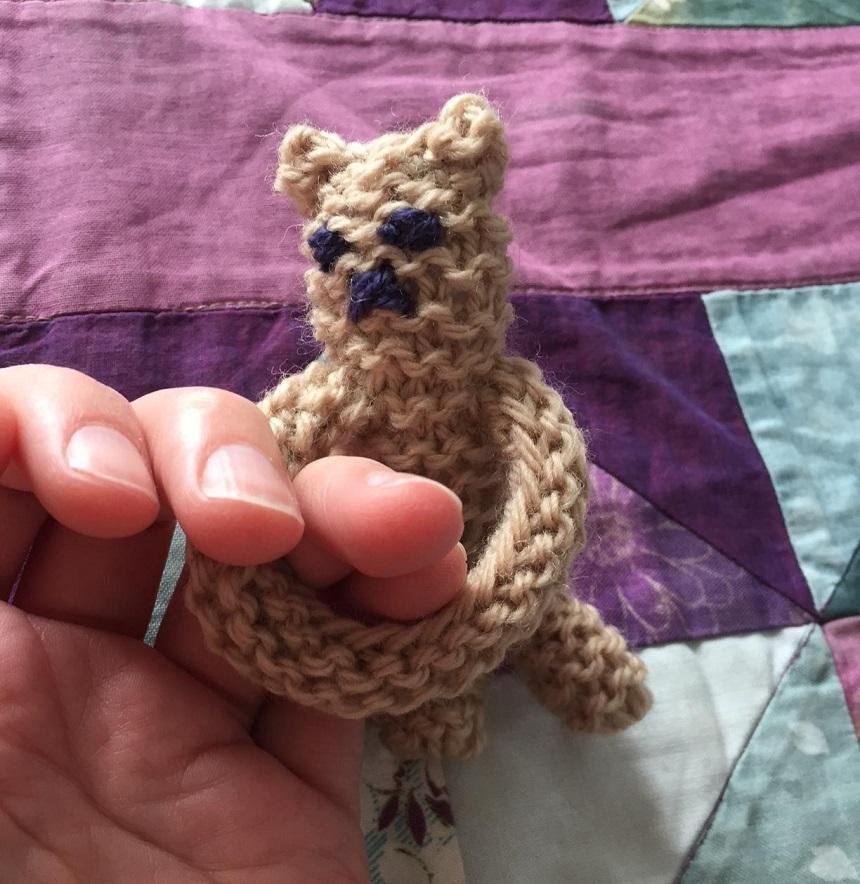 Snuggle Bear fidget toy gripping onto a person's fingers
