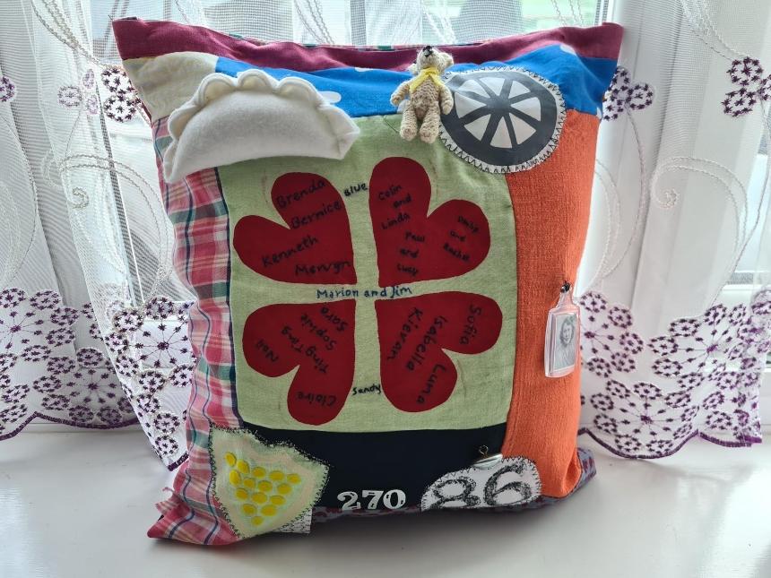 The front of Ting Ting's fidget cushion inspired by her granny, featuring four red hearts in a circle, a stitched Cornish pasty, and various other colourful objects