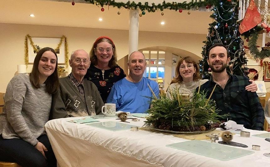 Rodger and family members sit around a dinner table with Christmas decorations