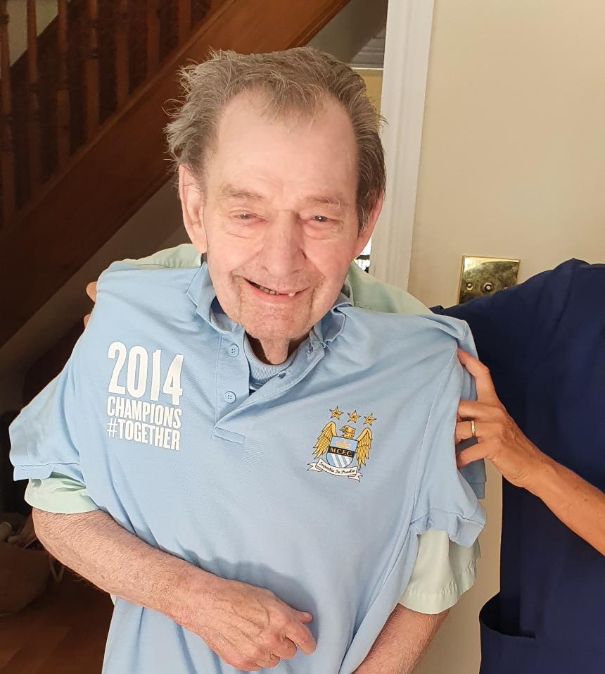 Stan pictured smiling, with a Manchester City shirt being held up in front of him