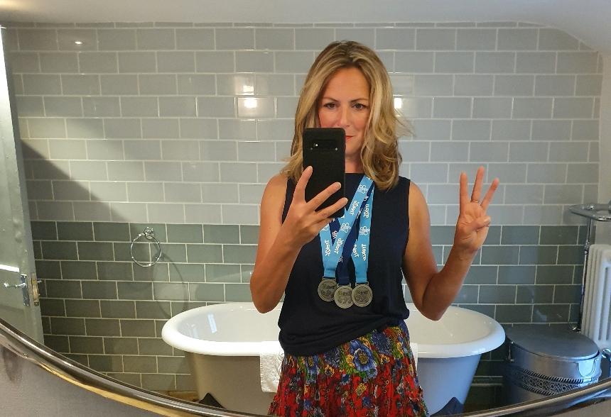 Julie taking a picture of herself in the mirror wearing her Trek26 medals