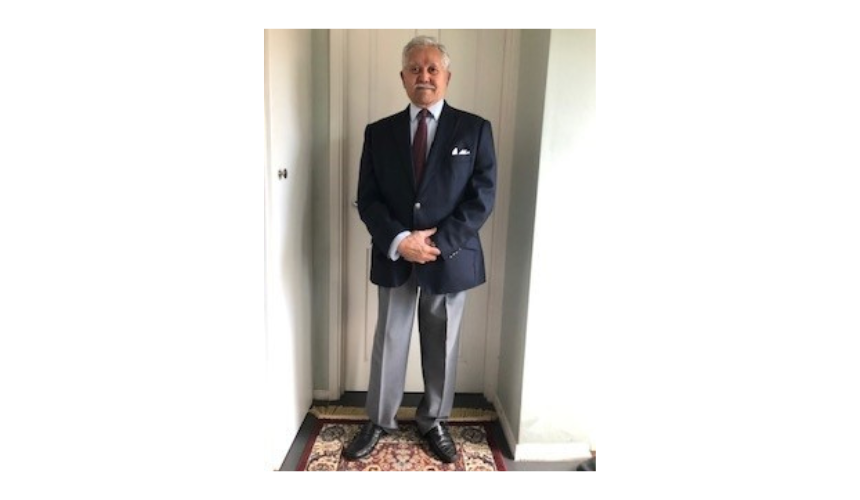 Afzal wearing a suit, standing in his hallway 