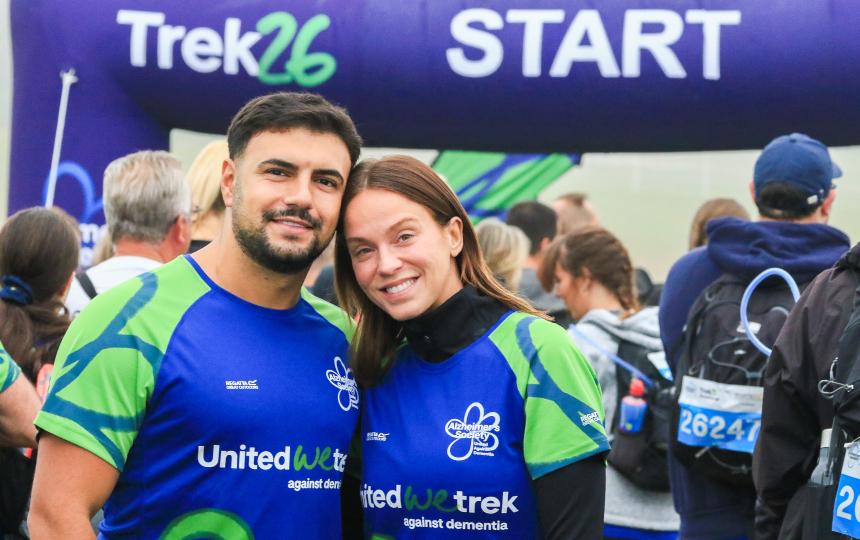 Vicky and Ercan smiling and wearing Trek26 shirts while under the Trek26 start line