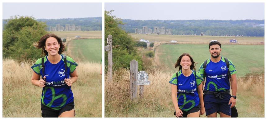 Vicky and Ercan smiling and wearing Trek26 shirts while on a trek with Stonehenge behind them