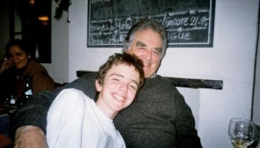 An old photograph of Charlie as a young boy with his grandad. Grandad has his arm round Charlie, and both are grinning.