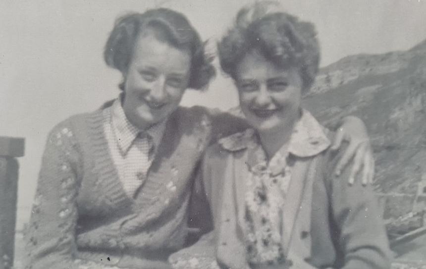An old photograph of young Hilary and Pauline, with their arm round one another 