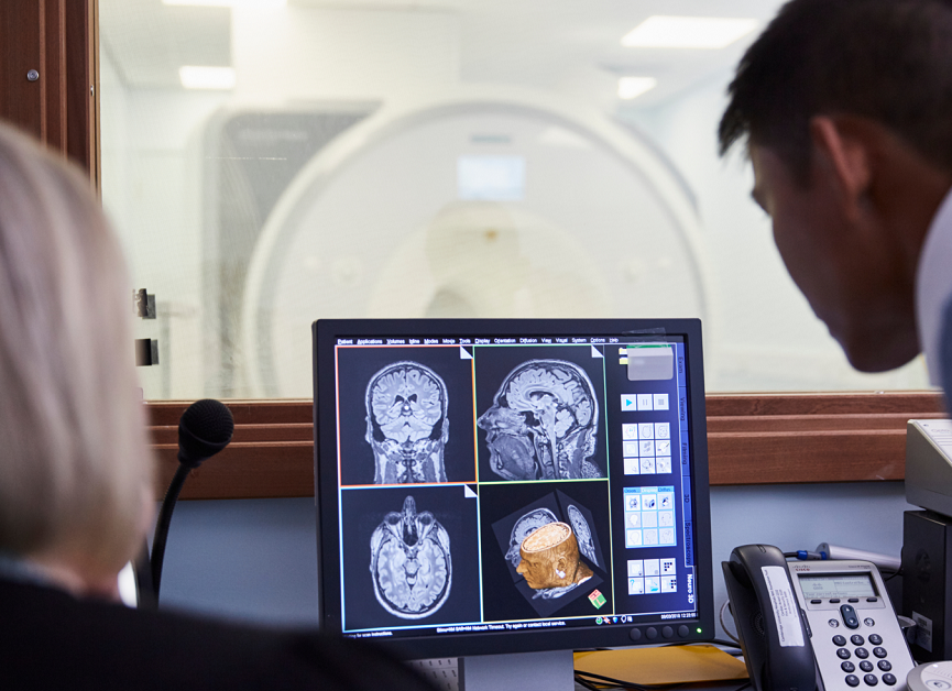 Two dementia researchers look at brain scans on a screen